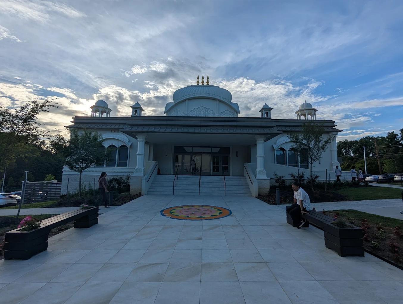 The temple facade at dusk, the rangoli lit on the entrance plaza